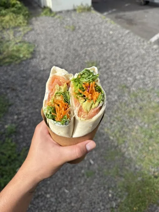 Wrap saumon-avocat Hotu, coupé en deux, tenu en main